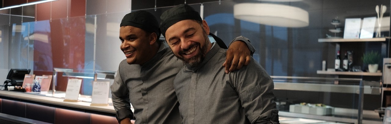 Two colleagues standing next to each other smiling and looking happy