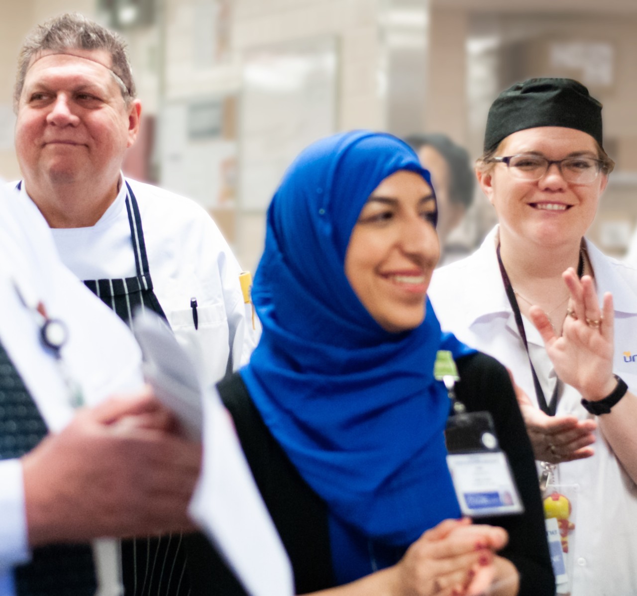 Group of colleagues standing clapping and smiling at a team meeting